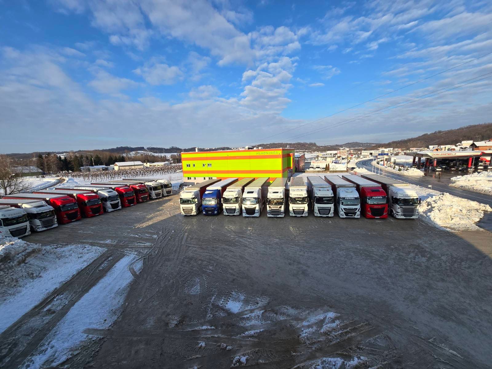 Aerodni snimak cijelog voznog parka Persel Transport — red kamiona DAF i Scania u snijegu ispred baze u Špionici