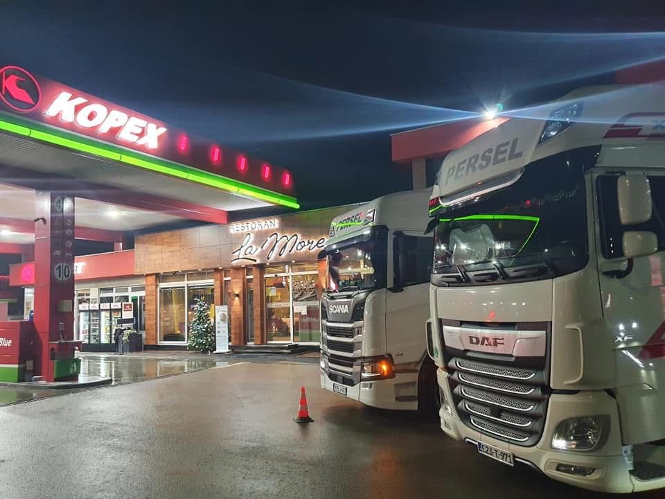 Bijeli Scania i DAF kamioni Persel Transport noću na benzinskoj stanici Kopex — atmosferska nocna snimka
